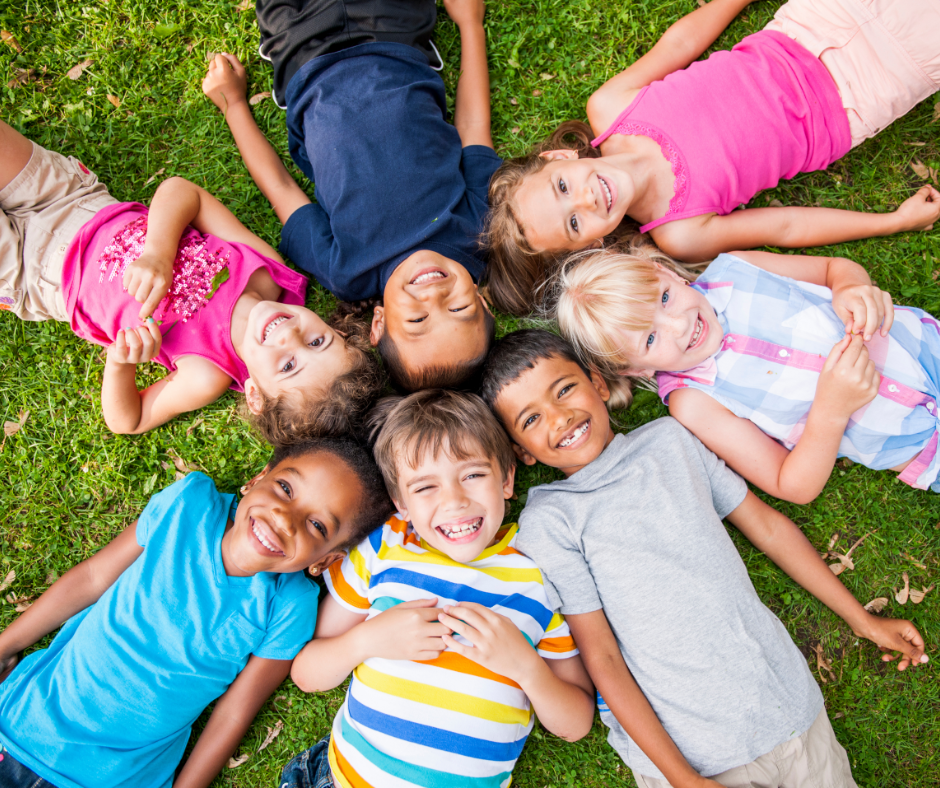 kids laying in circle on backs and smiling up at camera