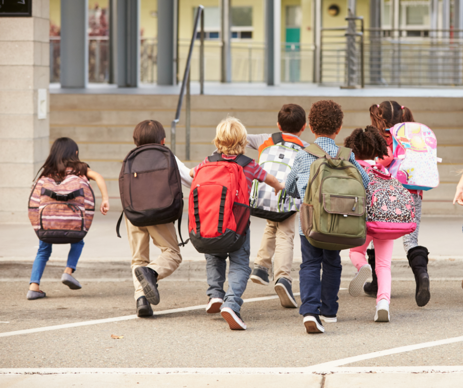 kids with backpacks running towards school in background