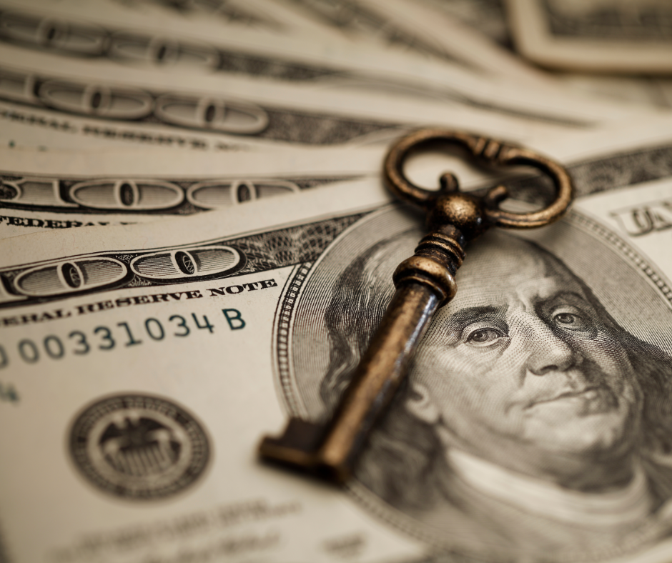 100 dollar bills with gold key laying on top