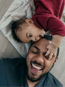 a man and a small girl lying down, with the small girl touching the man's forehead and the man smiling
