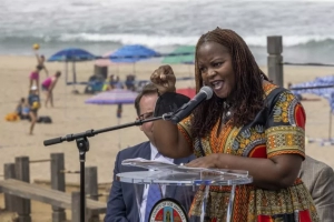 woman speaking behind podium with beach in the background