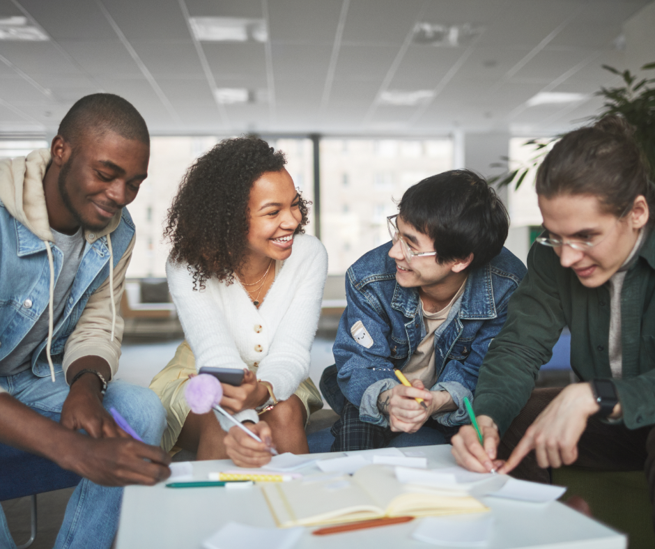 four diverse students sitting around table working together
