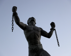 a statue of a person with arms in the air and broken chains from each wrist
