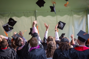 the backs of a group of graduates throwing their caps in the air