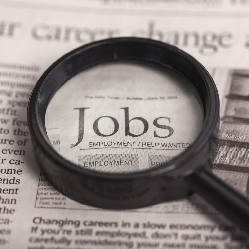 newspaper that reads "jobs" with a magnifying class on top of it