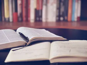 open books on a table with books on a shelf in the background