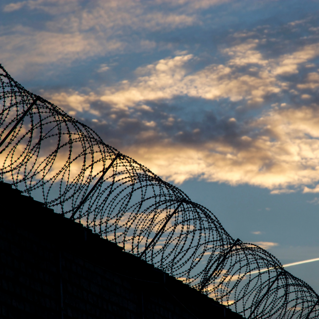 prison wall with barbed wire and sky in the background