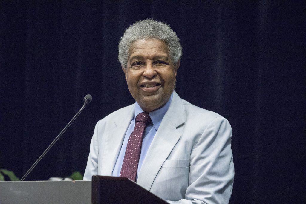 William "Sandy" Darity, Jr. speaking behind a podium