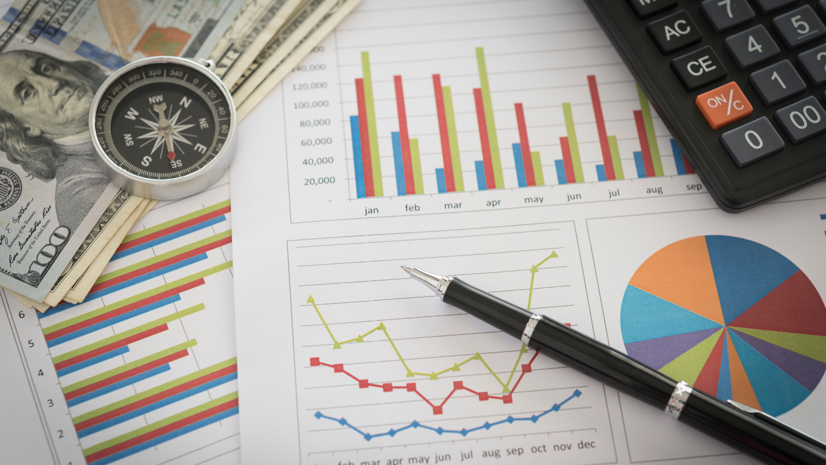 piece of paper with financial graphs, pen, calculator, money