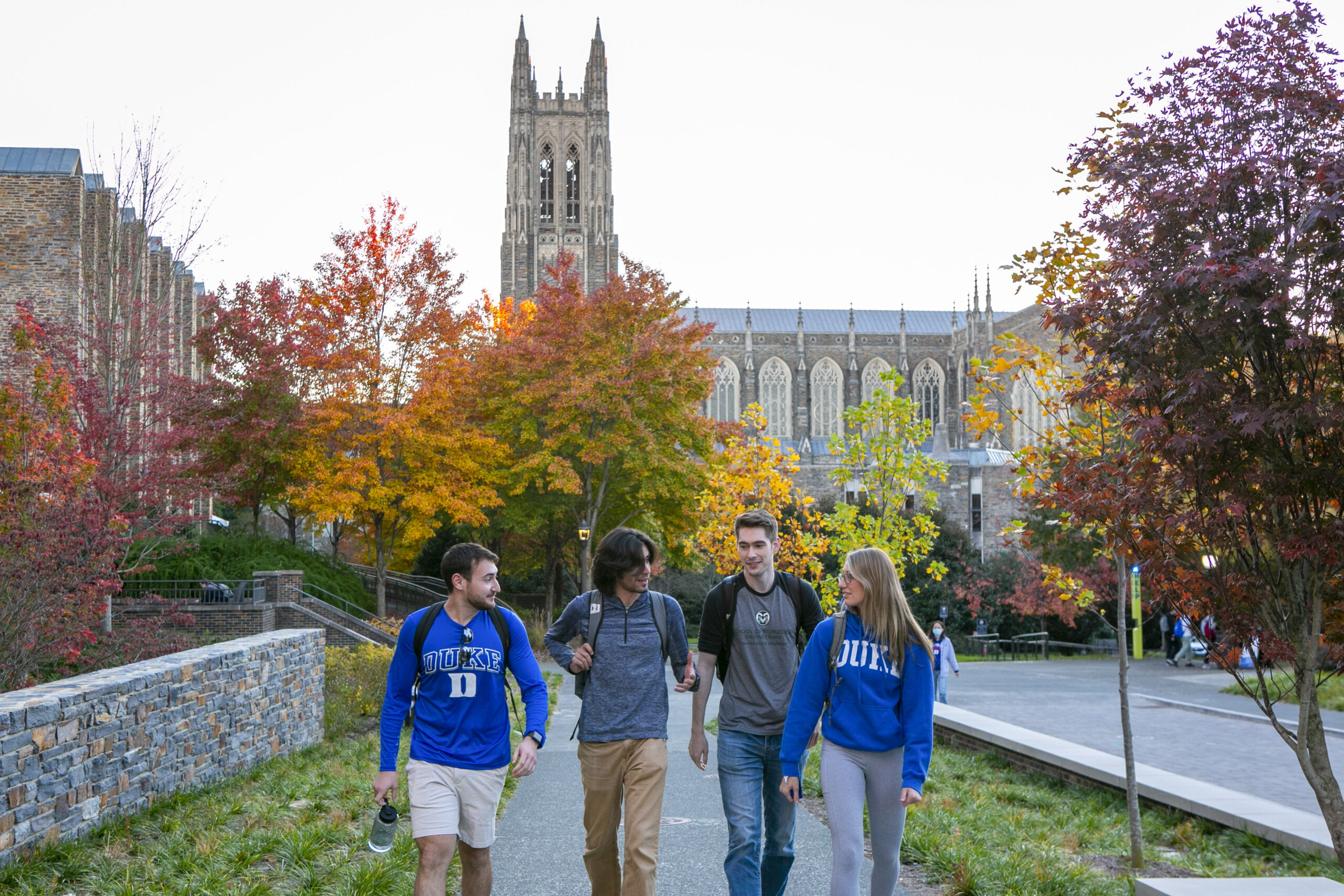 four students walking towards camera with Duke chapel in the background
